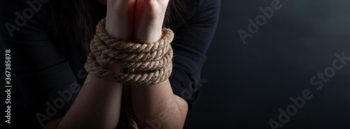 Fotografía woman hands tied with a coarse rope close-up black background