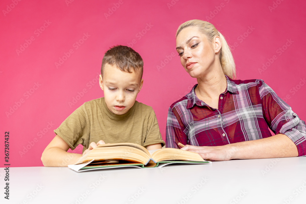 Mother helping her son with homework over isolated pink background. Distant education. Mother helping her son with homework over isolated pink background. Distant education.