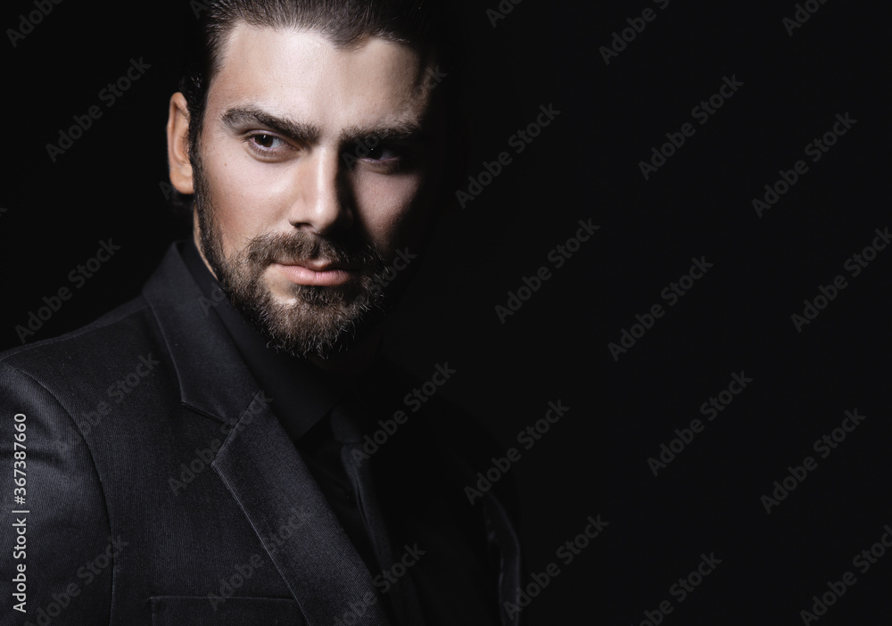 Strict male portrait. The guy in the classic black suit. Half face in the light. Strict male portrait. The guy in the classic black suit. Half face in the light.