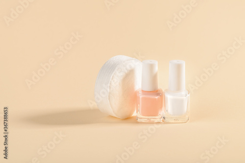 White and pale pink nail polish and cotton pads on a powdery color background. Manicure  pedicure  nail care products. Copy space.