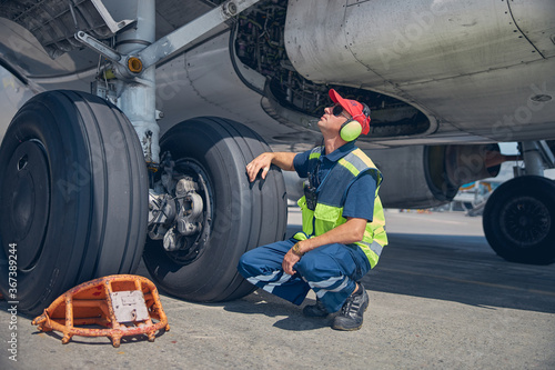 Slika na platnu Qualified young technician inspecting the undercarriage axle