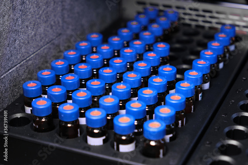 Glass vials with blue caps are in the rack of HPLC system with autosampler. Separation of compounds at chemical or clinical laboratory. Scientific and research work. Development of pharmaceuticals.