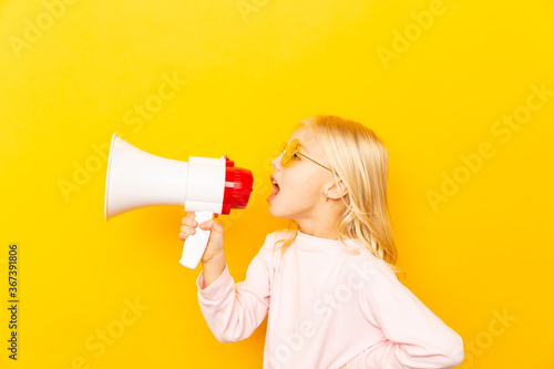 Kid shouting through megaphone. Communication concept. yellow background as copy space for your text.