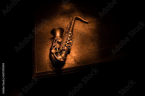Fotografia Alto gold sax miniature with colorful toned light on foggy background