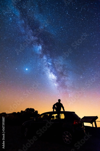 Silhouette of a seated man looking at the stars and the Milky Way on a summer night in the sky of Tenerife