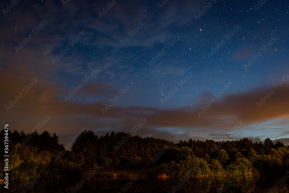 Evening landscape: first stars and a comet Neowise over a forest lake just after sunset. Long exposure night landscape. 
