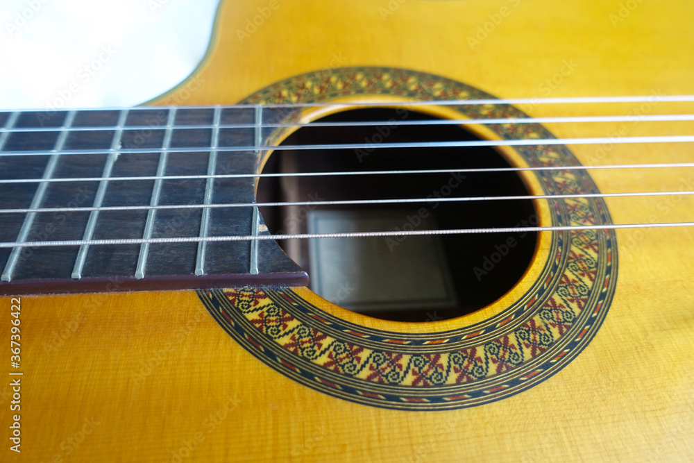 Close up of vibrant yellow guitar body with strings. Detail of acoustic guitar hole and strings. Close up of vibrant yellow guitar body with strings. Detail of acoustic guitar hole and strings.