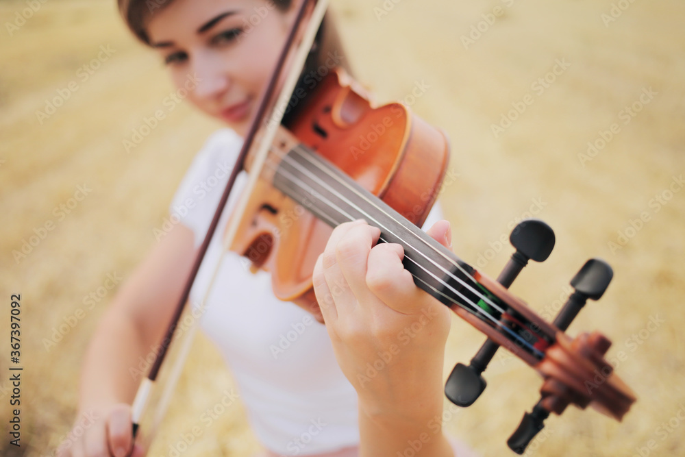 Beautiful romantic girl with loose hair playing the violin in the field. Beautiful romantic girl with loose hair playing the violin in the field.