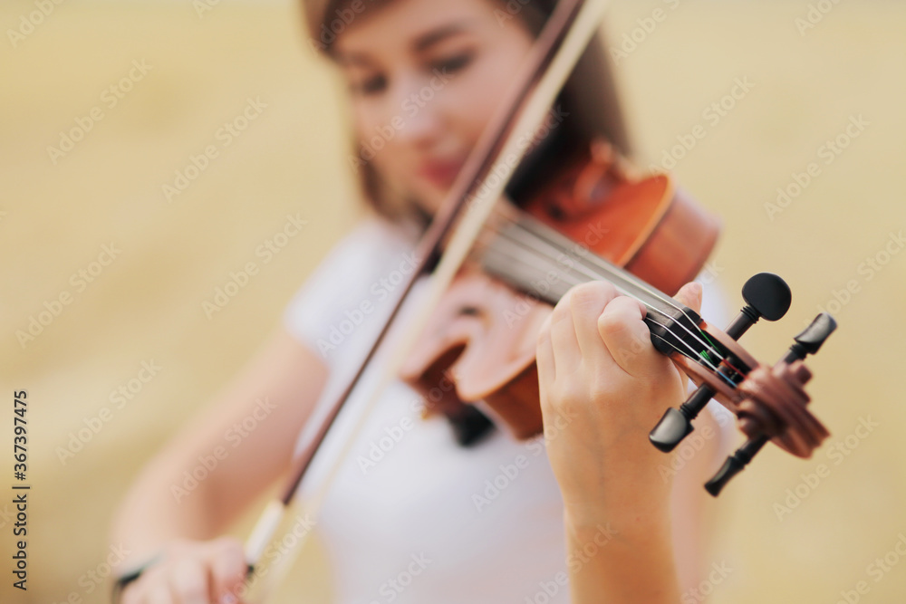 Beautiful romantic girl with loose hair playing the violin in the field. Beautiful romantic girl with loose hair playing the violin in the field.