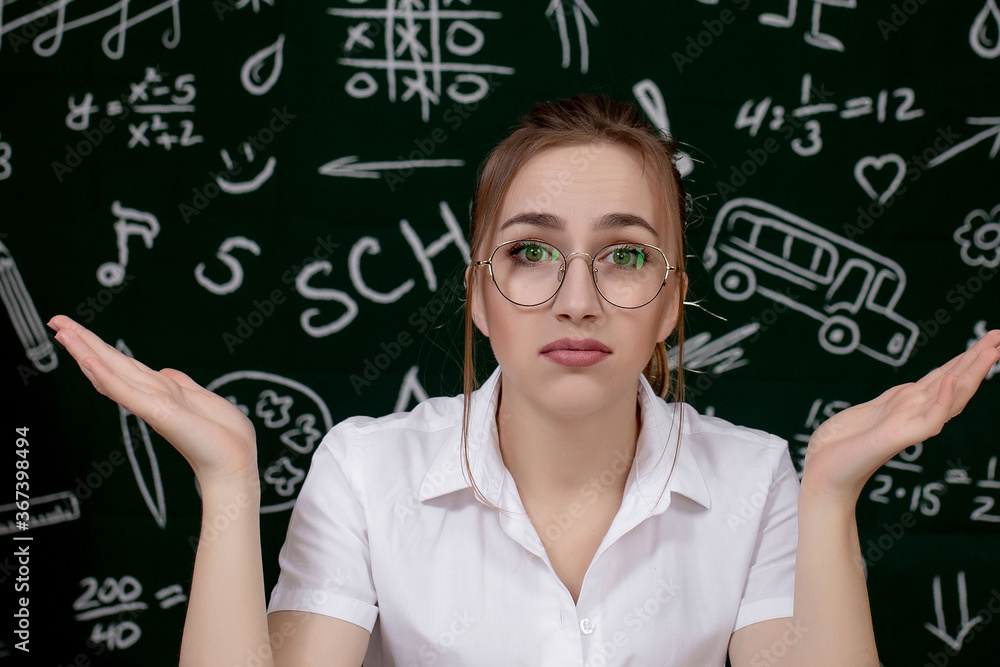Young teacher is sitting near blackboard in classroom Young teacher is sitting near blackboard in classroom