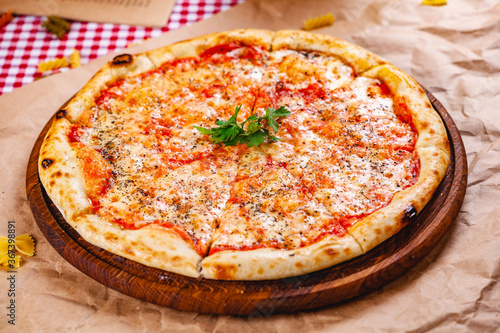 Italian Pizza Margherita with tomatoes and mozzarella cheese on wooden cutting board. Close up