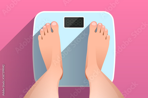 Top view of feet of woman standing on bathroom scales photo