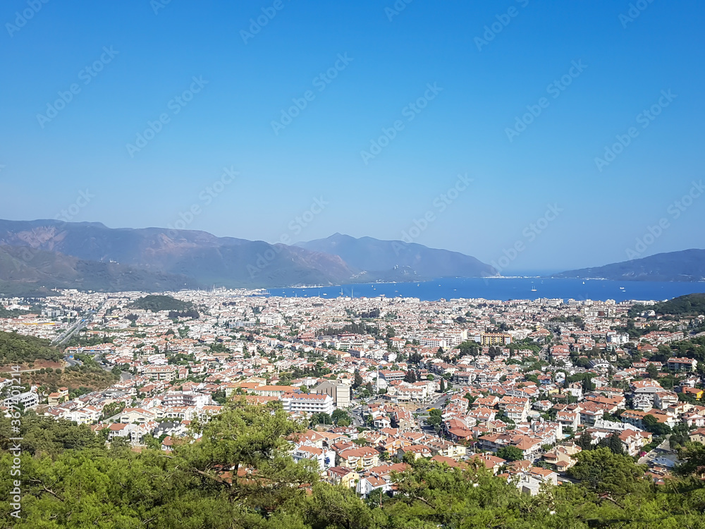 beautiful view over the sunny city, sea and mountains, blue sky and green trees