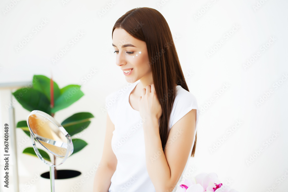 Facial skin care, young woman applies face cream in the spacious bathroom of a luxury hotel Facial skin care, young woman applies face cream in the spacious bathroom of a luxury hotel