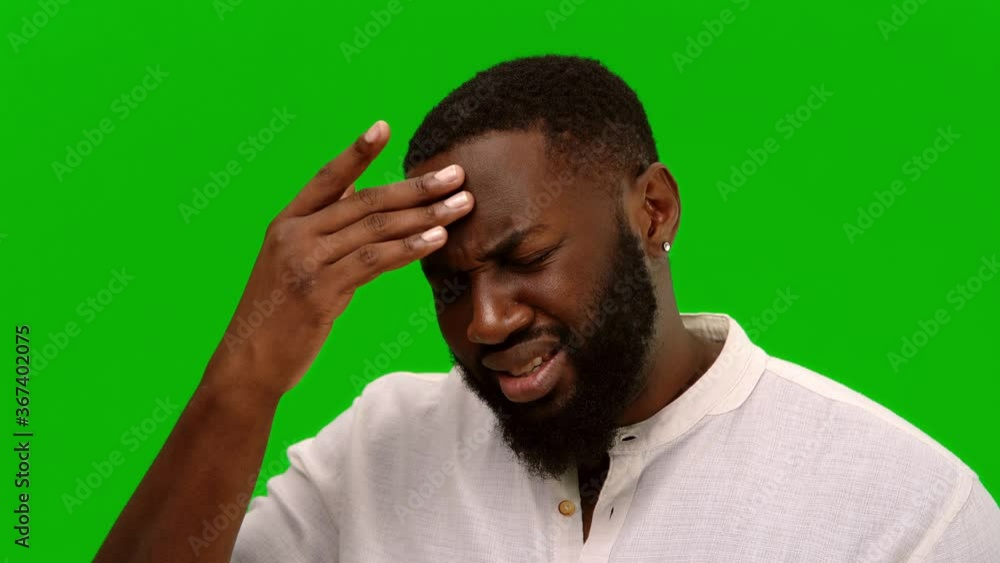 Tired man suffering from painful headache and stress. African american man in white shirt holding hand on forehead on green background. Alpha channel. Medical concept. Alpha channel Tired man suffering from painful headache and stress. African american man in white shirt holding hand on forehead on green background. Alpha channel. Medical concept. Alpha channel