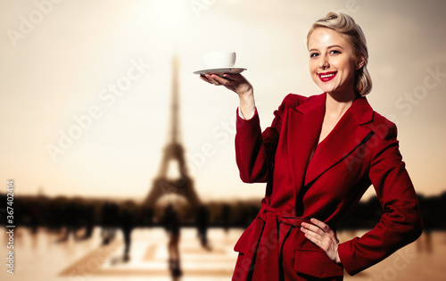 Blonde girl in red coat and vintage hairdress with cup of coffee