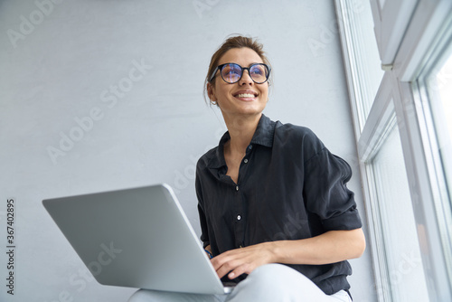 Foto Jolly young woman using notebook for fun indoors
