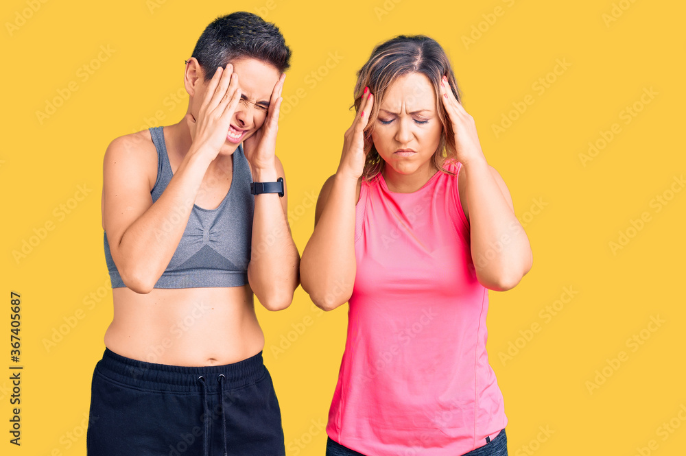 Couple of women wearing sportswear with hand on head, headache because stress. suffering migraine. Couple of women wearing sportswear with hand on head, headache because stress. suffering migraine.