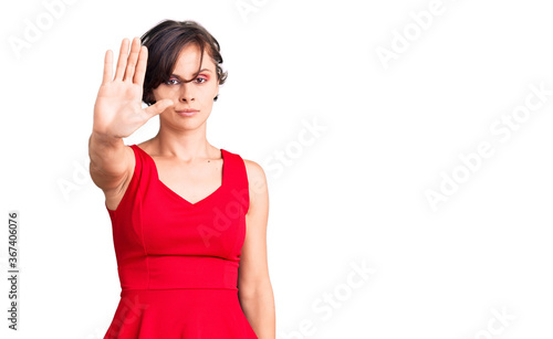 Beautiful young woman with short hair wearing casual style with sleeveless shirt doing stop sing with palm of the hand. warning expression with negative and serious gesture on the face. © Krakenimages.com