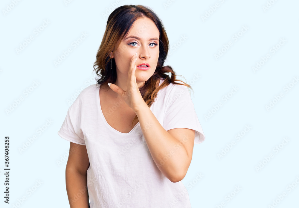 Young beautiful caucasian woman wearing casual white tshirt hand on mouth telling secret rumor, whispering malicious talk conversation Young beautiful caucasian woman wearing casual white tshirt hand on mouth telling secret rumor, whispering malicious talk conversation