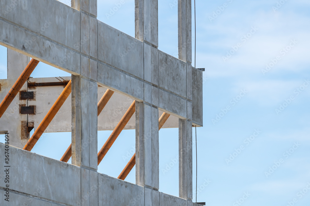 The corner of a commercial building made of precast concrete walls. The spaces between the concrete pillars are for windows. The grunge and textured panels are on a construction site. The corner of a commercial building made of precast concrete walls. The spaces between the concrete pillars are for windows. The grunge and textured panels are on a construction site.