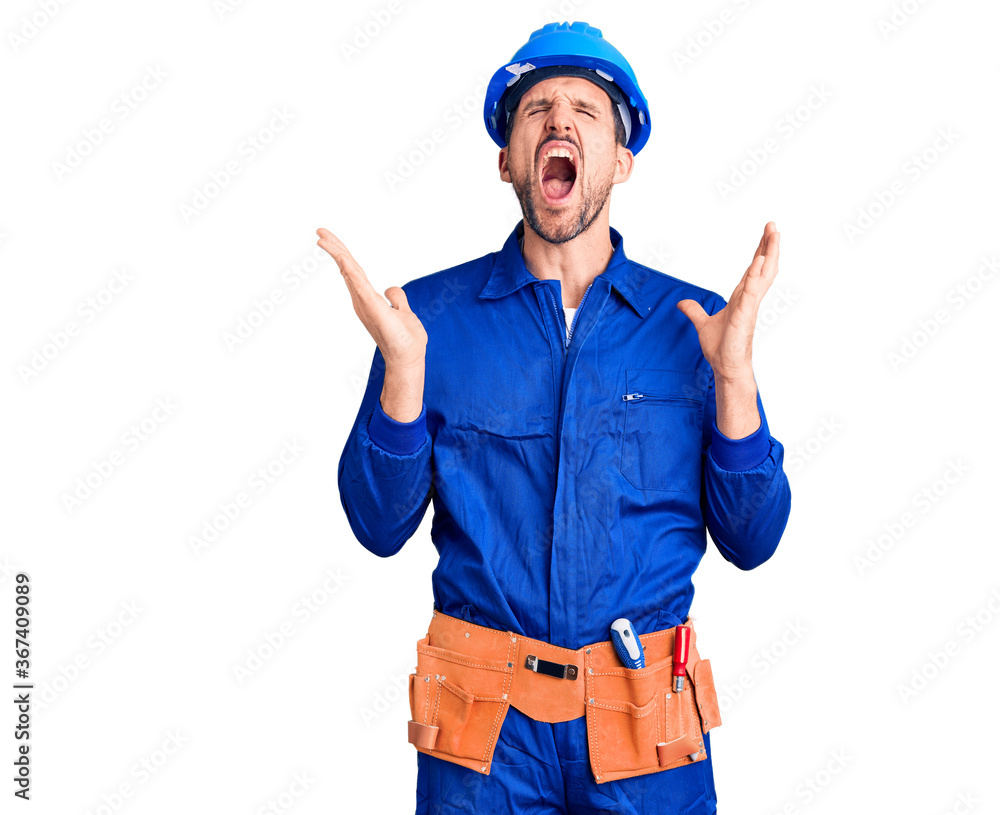 Young handsome man wearing worker uniform and hardhat celebrating mad and crazy for success with arms raised and closed eyes screaming excited. winner concept Young handsome man wearing worker uniform and hardhat celebrating mad and crazy for success with arms raised and closed eyes screaming excited. winner concept