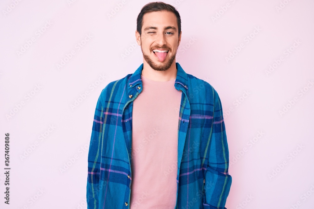Fototapeta premium Young handsome man wearing casual clothes sticking tongue out happy with funny expression. emotion concept.