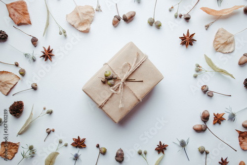Autumn creative holiday present. Handmade paper gift box with foliage dried leaves, pine cones and acorns. Thanksgiving day, fall background. Copy space