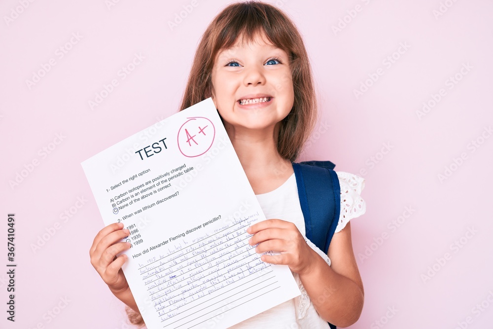 Little caucasian kid girl with long hair showing a passed exam from primary school looking positive and happy standing and smiling with a confident smile showing teeth Little caucasian kid girl with long hair showing a passed exam from primary school looking positive and happy standing and smiling with a confident smile showing teeth