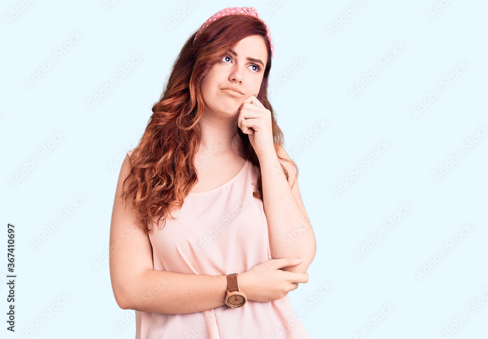 Young beautiful woman wearing casual clothes and diadem serious face thinking about question with hand on chin, thoughtful about confusing idea Young beautiful woman wearing casual clothes and diadem serious face thinking about question with hand on chin, thoughtful about confusing idea