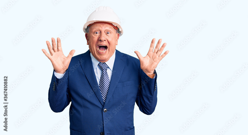 Senior handsome grey-haired man wearing suit and architect hardhat celebrating crazy and amazed for success with arms raised and open eyes screaming excited. winner concept Senior handsome grey-haired man wearing suit and architect hardhat celebrating crazy and amazed for success with arms raised and open eyes screaming excited. winner concept