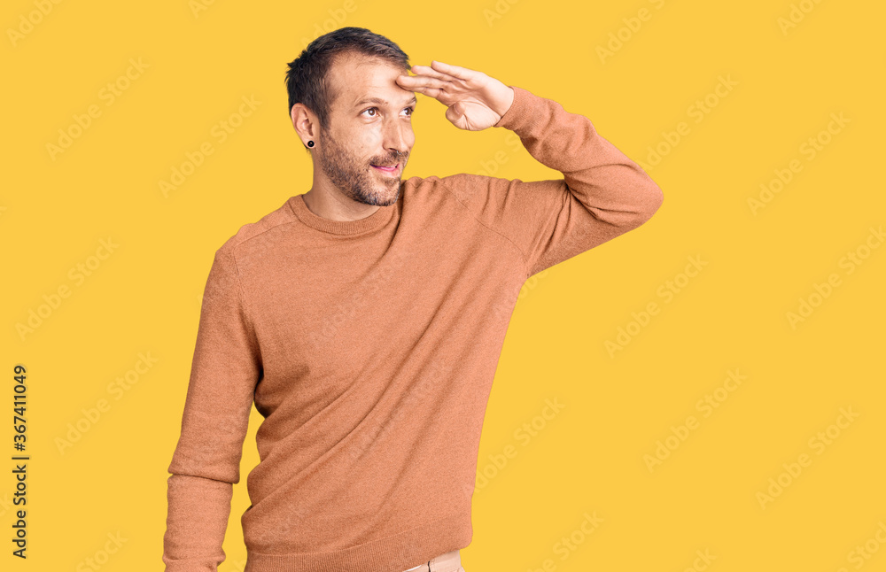 Young handsome man wearing casual clothes very happy and smiling looking far away with hand over head. searching concept. Young handsome man wearing casual clothes very happy and smiling looking far away with hand over head. searching concept.