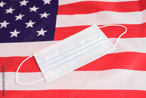 Disposable surgical mask on the background of the American flag, country with rise in the regrowth of infected.