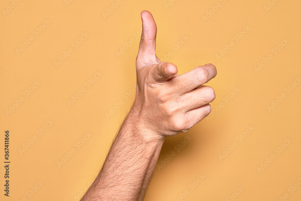 Hand of caucasian young man showing fingers over isolated yellow background pointing forefinger to the camera, choosing and indicating towards direction