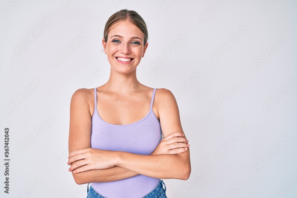 Young blonde girl wearing casual style with sleeveless shirt happy face smiling with crossed arms looking at the camera. positive person. Young blonde girl wearing casual style with sleeveless shirt happy face smiling with crossed arms looking at the camera. positive person.