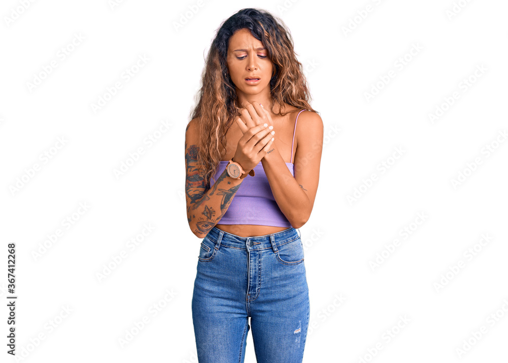 Young hispanic woman with tattoo wearing casual clothes suffering pain on hands and fingers, arthritis inflammation Young hispanic woman with tattoo wearing casual clothes suffering pain on hands and fingers, arthritis inflammation