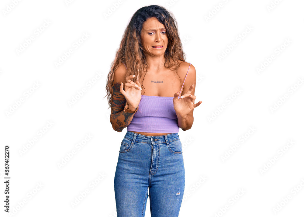 Young hispanic woman with tattoo wearing casual clothes disgusted expression, displeased and fearful doing disgust face because aversion reaction. Young hispanic woman with tattoo wearing casual clothes disgusted expression, displeased and fearful doing disgust face because aversion reaction.