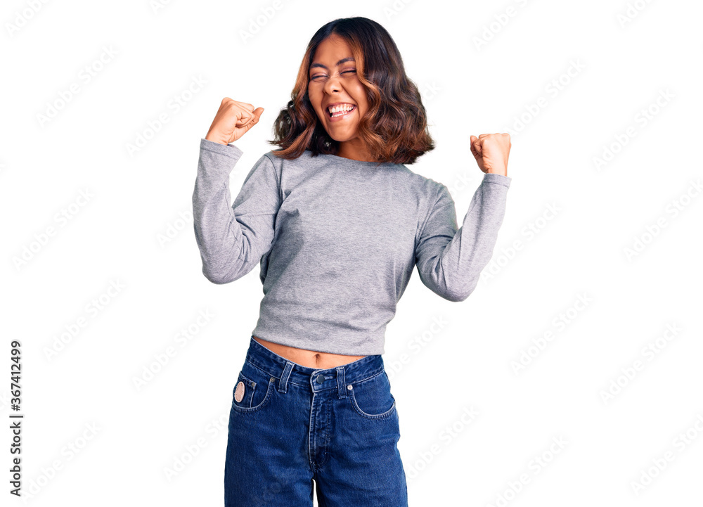 Young beautiful mixed race woman wearing casual clothes very happy and excited doing winner gesture with arms raised, smiling and screaming for success. celebration concept. Young beautiful mixed race woman wearing casual clothes very happy and excited doing winner gesture with arms raised, smiling and screaming for success. celebration concept.