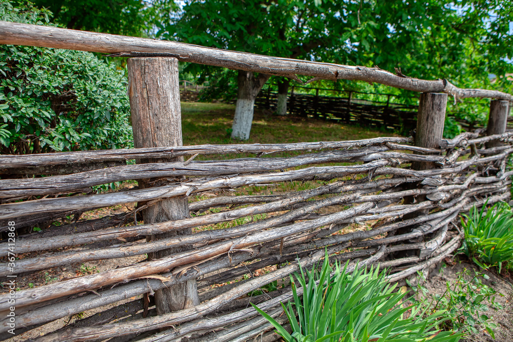 Rustic yard with fence in traditional style . Wicker fence Rustic yard with fence in traditional style . Wicker fence
