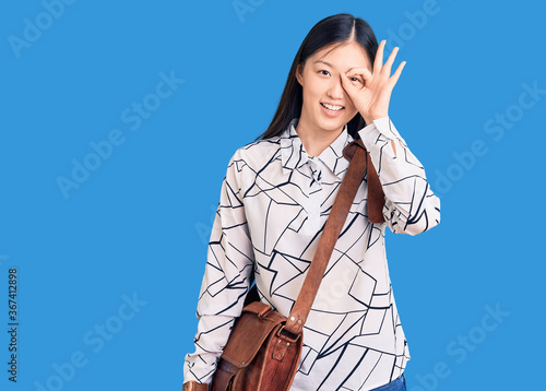 Young beautiful chinese woman holding briefcase smiling happy doing ok sign with hand on eye looking through fingers © Krakenimages.com