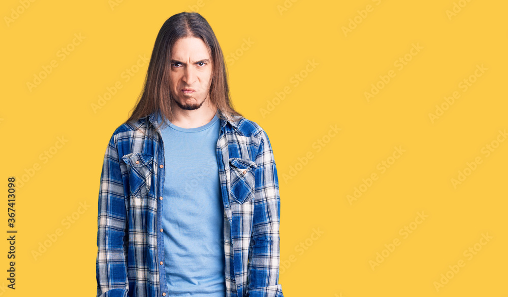 Young adult man with long hair wearing casual shirt skeptic and nervous, frowning upset because of problem. negative person.