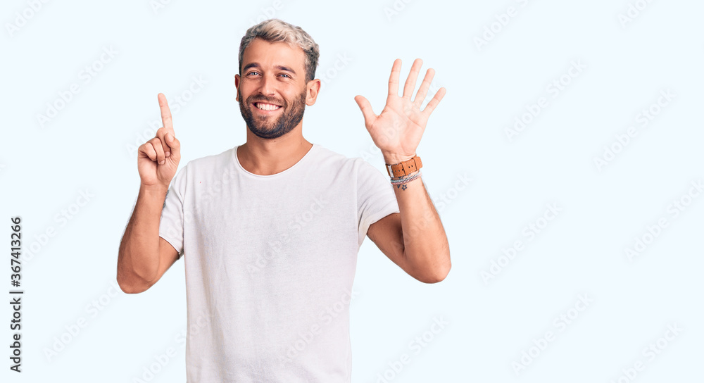 Fototapeta premium Young handsome blond man wearing casual t-shirt showing and pointing up with fingers number six while smiling confident and happy.
