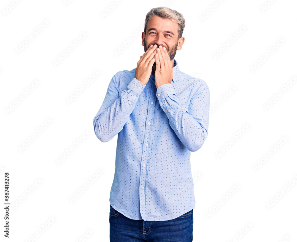 Young handsome blond man wearing elegant shirt laughing and embarrassed giggle covering mouth with hands, gossip and scandal concept Young handsome blond man wearing elegant shirt laughing and embarrassed giggle covering mouth with hands, gossip and scandal concept