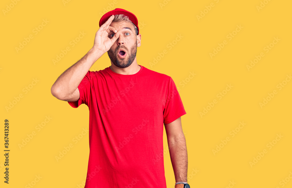 Young handsome blond man wearing t-shirt and cap doing ok gesture shocked with surprised face, eye looking through fingers. unbelieving expression. Young handsome blond man wearing t-shirt and cap doing ok gesture shocked with surprised face, eye looking through fingers. unbelieving expression.