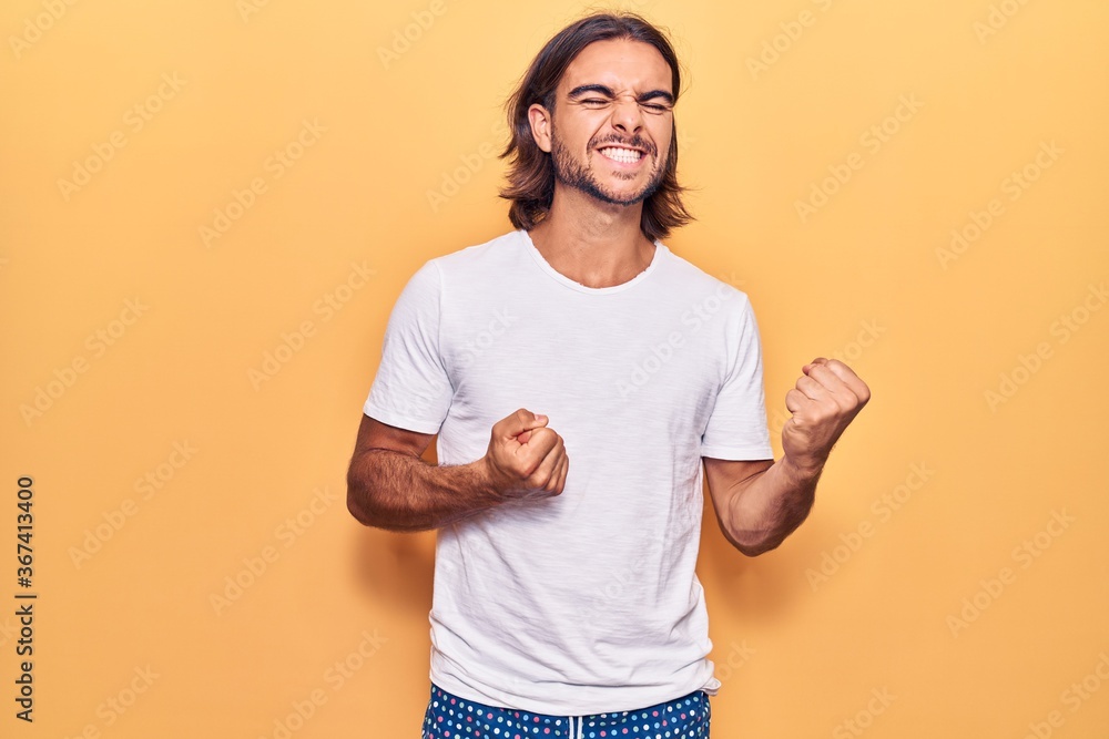 Young handsome man wearing casual clothes excited for success with arms raised and eyes closed celebrating victory smiling. winner concept. Young handsome man wearing casual clothes excited for success with arms raised and eyes closed celebrating victory smiling. winner concept.
