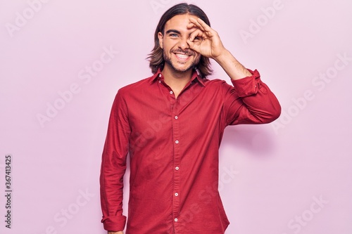 Young handsome man wearing business clothes doing ok gesture with hand smiling, eye looking through fingers with happy face.