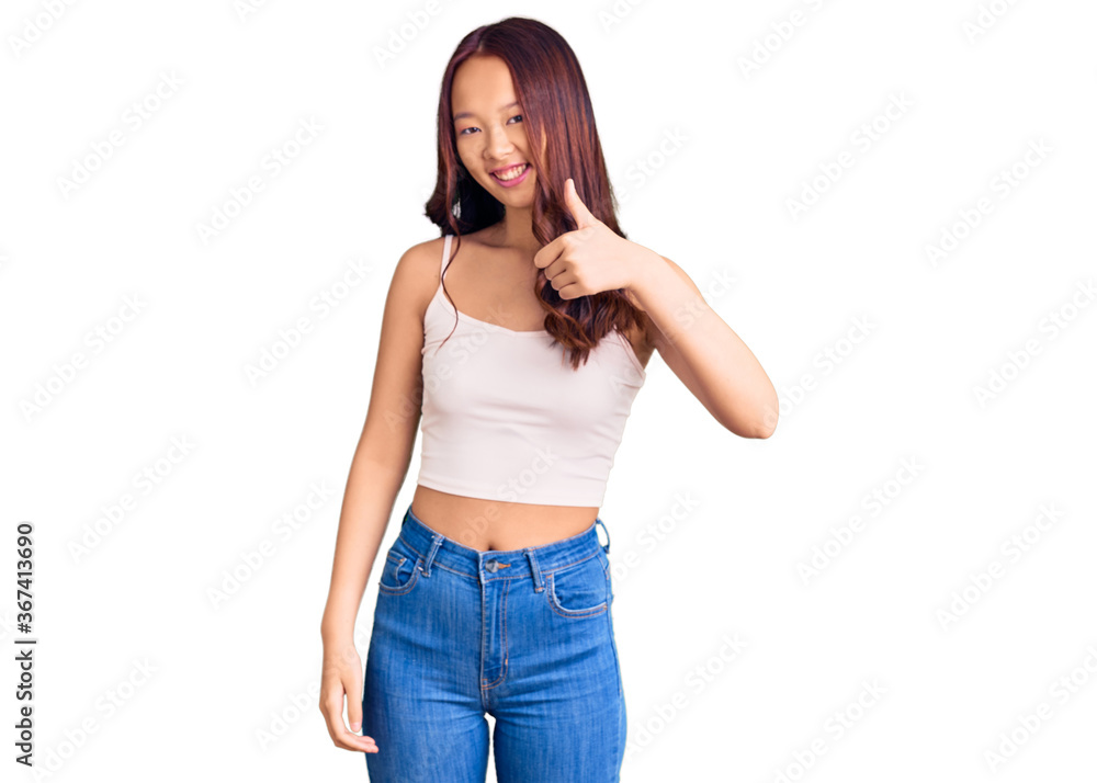 Young beautiful chinese girl wearing casual clothes doing happy thumbs up gesture with hand. approving expression looking at the camera showing success. Young beautiful chinese girl wearing casual clothes doing happy thumbs up gesture with hand. approving expression looking at the camera showing success.
