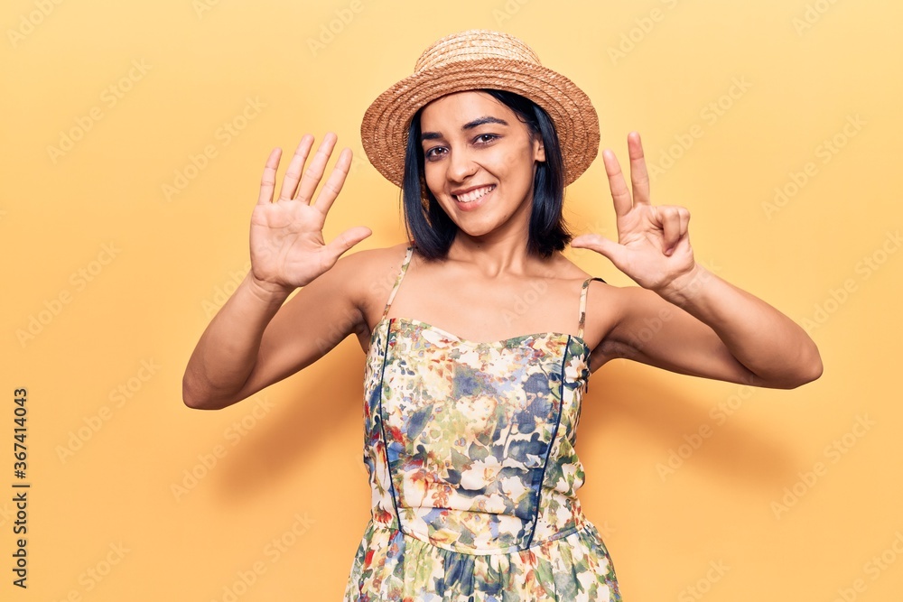 Young beautiful latin woman wearing summer hat showing and pointing up with fingers number eight while smiling confident and happy. Young beautiful latin woman wearing summer hat showing and pointing up with fingers number eight while smiling confident and happy.