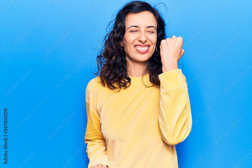 Fototapeta premium Young beautiful hispanic woman wearing casual clothes celebrating surprised and amazed for success with arms raised and eyes closed