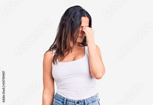 Young beautiful brunette woman wearing casual sleeveless t-shirt tired rubbing nose and eyes feeling fatigue and headache. stress and frustration concept.
